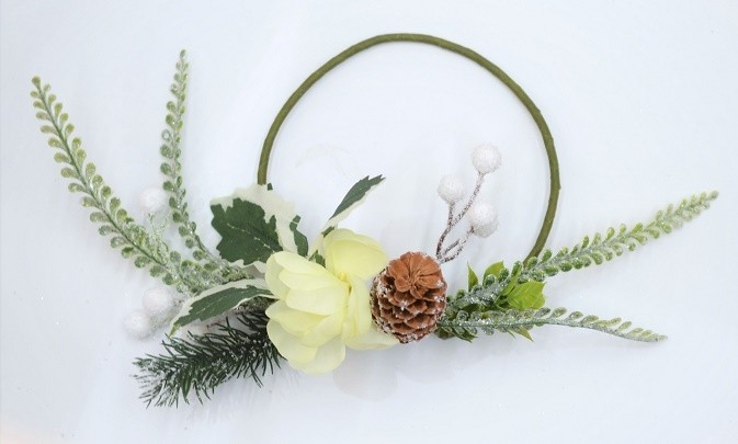 22081 -  Beautiful Cream flower in a wintery wreath with a display of snowy pine needles, cones, berries and green leaves. Floral decoration.  Size   Approx 24cm dia