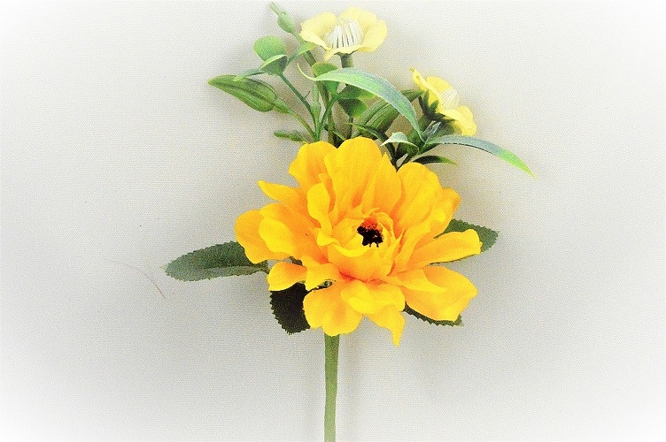 33009 - Bright Yellow floral arrangement accompanied with delicate Primrose flowers and leaves.  Height  17cms ,  Width  12cms   (approx)
